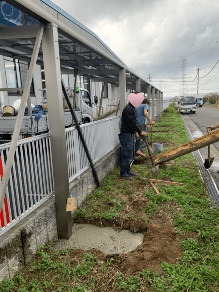 サイクルポートの柱用の穴にコンクリートを流し込んでいる写真